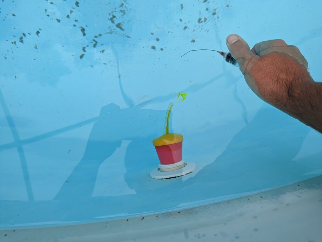 Pool leak detection dye test — dye injected near a pool fitting is pulled toward the leak source confirming its location in still water